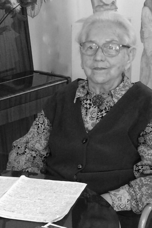 Czarno-białe zdjęcie. Kobieta siedząca przy stoliku. 