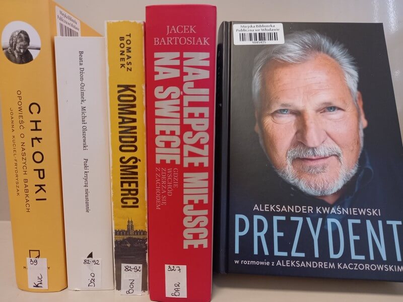 Cztery książki stojące, widoczne grzbiety; jedna książka stojąca, widoczna okładka: Aleksander Kwaśniewski w rozmowie z Aleksandrem Kaczorowskim.