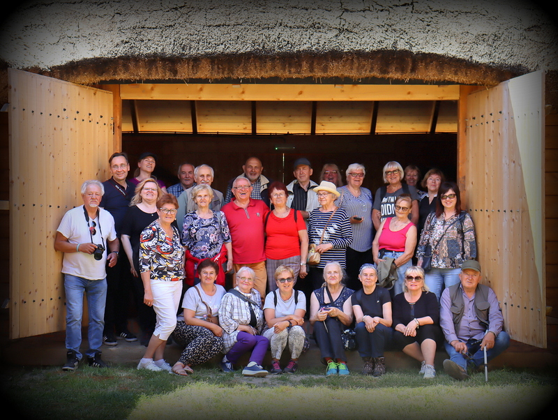 Grupa ludzi stojąca w wierzejach stodoły, pozująca do zbiorowego zdjęcia