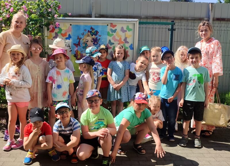 Grupa dzieci wraz z paniami pozują do wspólnej fotografii w Letniej Galerii SMO.