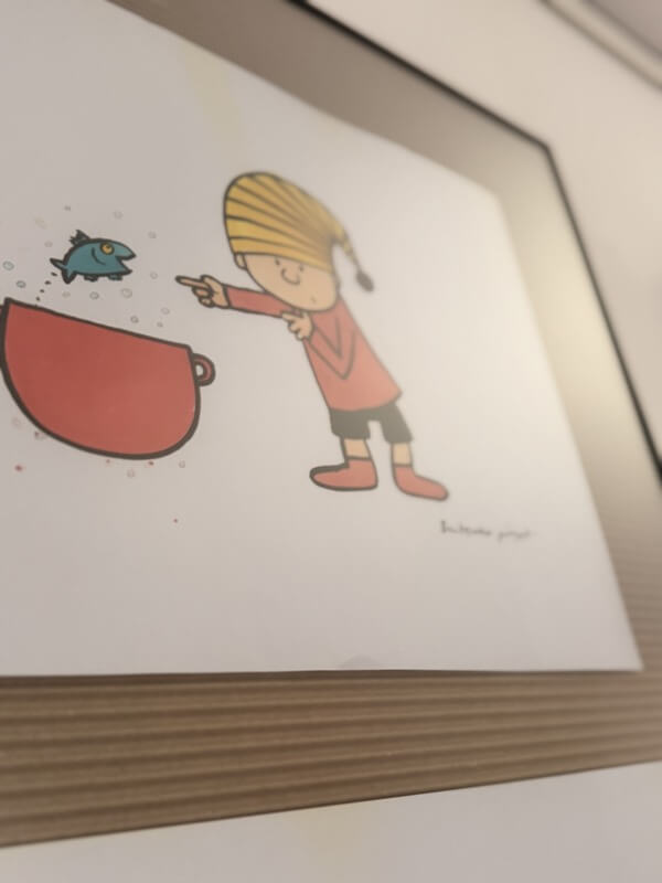 Ilustracja autorstwa Bohdana Butenki przedstawiająca postać Gapiszona. Chłopiec w czerwonej bluzce i paski na czapce z pomponem wskazuje palcem na małą, niebieską rybkę wyskakującą z czerwonej miski.